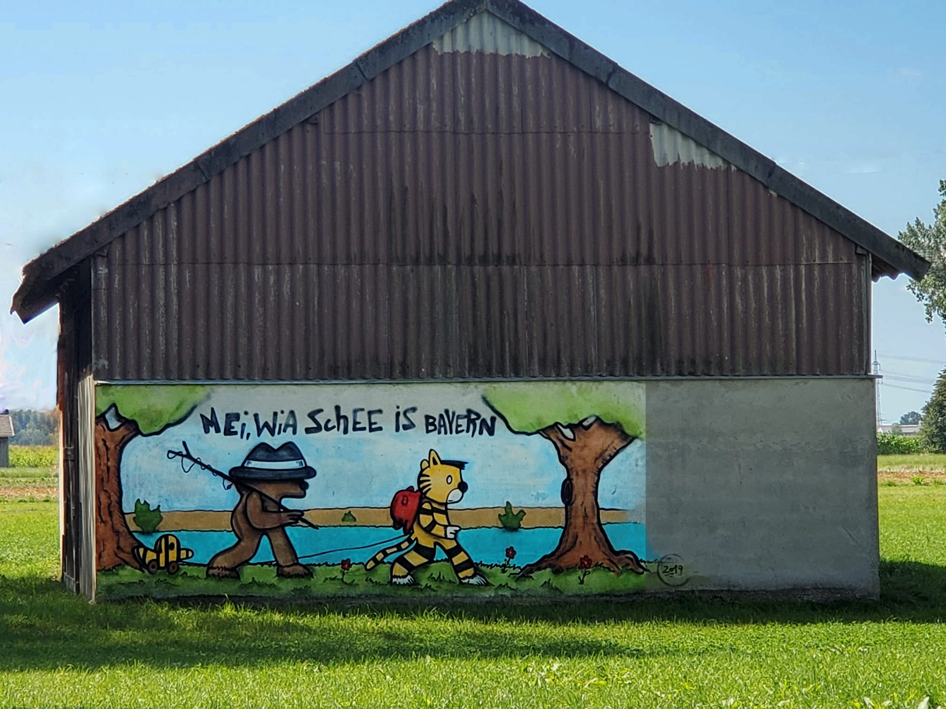 Ein Haus mit einem großen Cartoon-Bild, das sagt: "Mei, wia schee is Bayern"